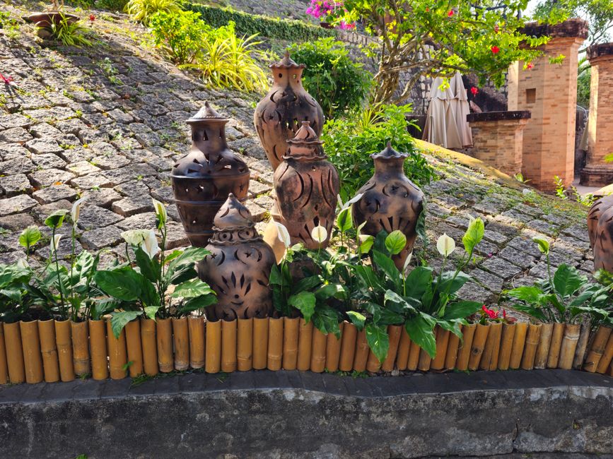 Terracotta garden sculptures amid vibrant greenery.